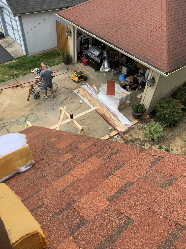Roofing crew cutting materials beside a home during a roofing project